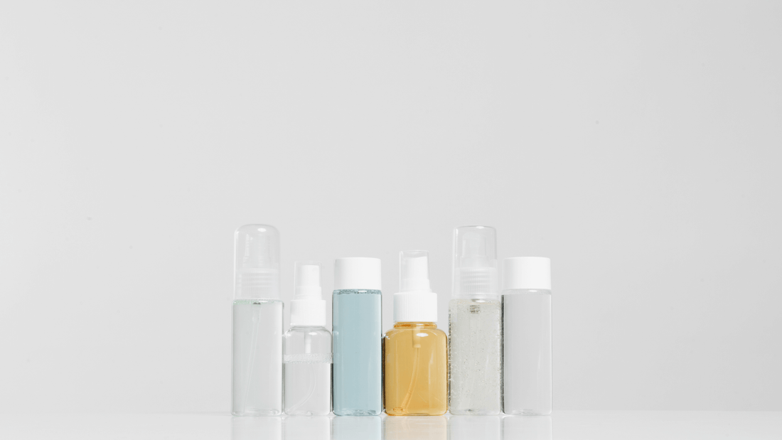 Row of minimalist skincare bottles in neutral tones on a clean white background, illustrating a simple and effective skincare approach.